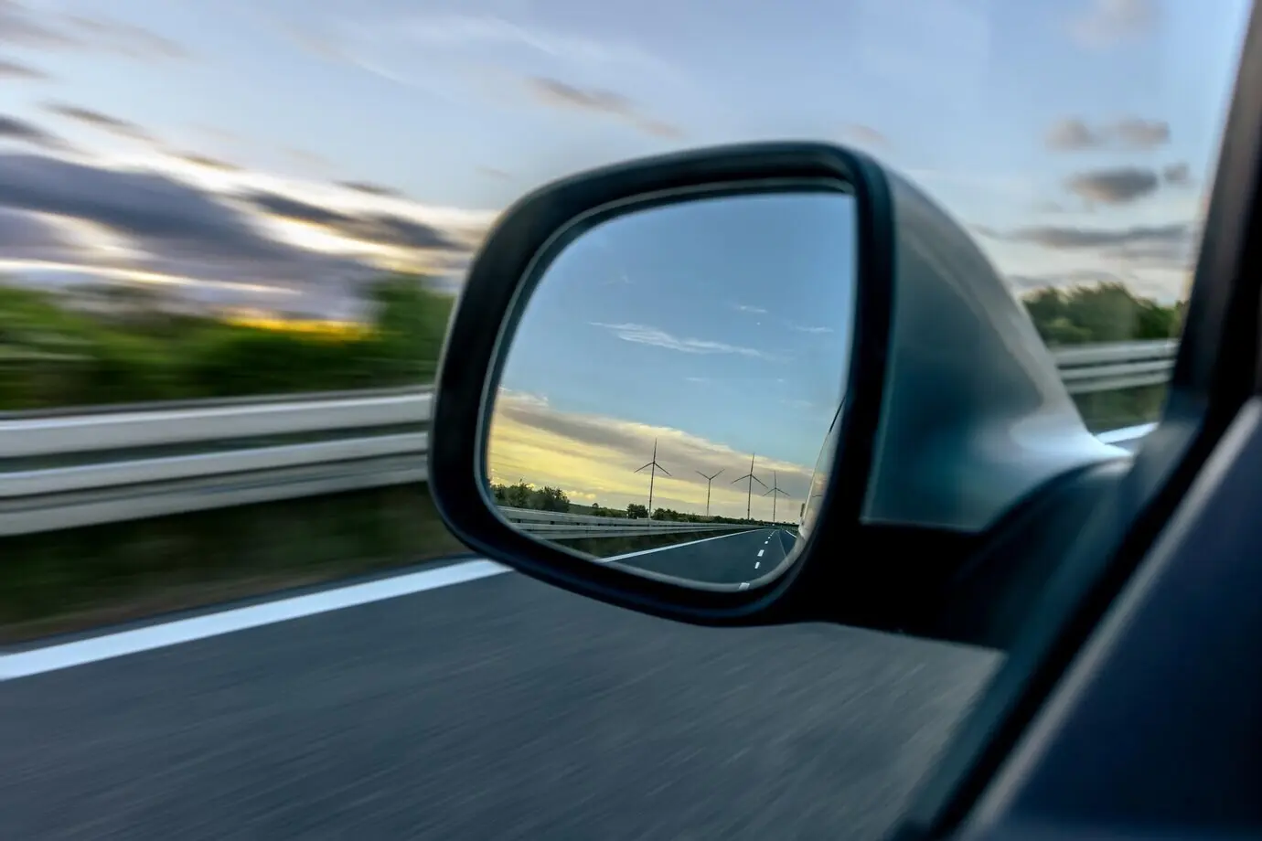 Auto-Seitenspiegel, Windräder am Horizont, Geschwindigkeit und Nachhaltigkeit.